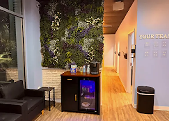 Barra de café y bebidas junto a una pared de plantas vivas